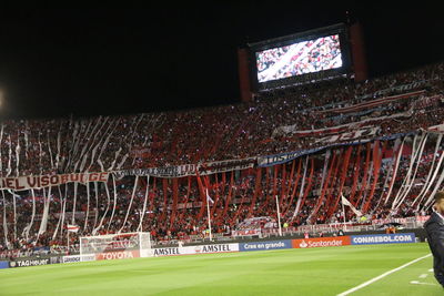 Group of people playing soccer on field at night