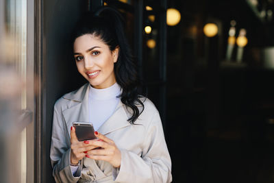 Portrait of smiling young woman using mobile phone