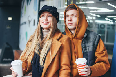 Young couple holding coffee sitting in cafe