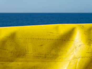Close-up of yellow blue sea against sky