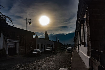 Street amidst buildings against sky during sunset