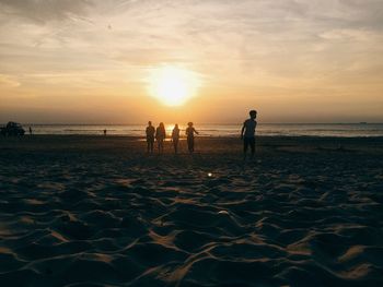 People on beach against sky during sunset