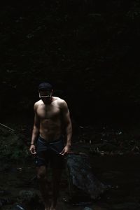 Shirtless man standing in forest