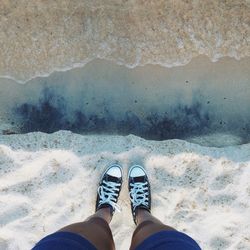 Low section of woman standing on shore at beach