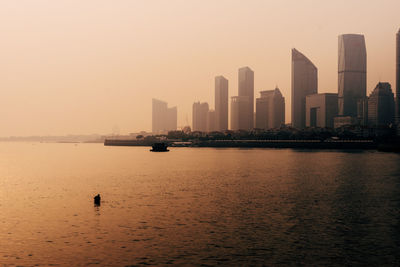 Scenic view of city by sea against sky during sunset