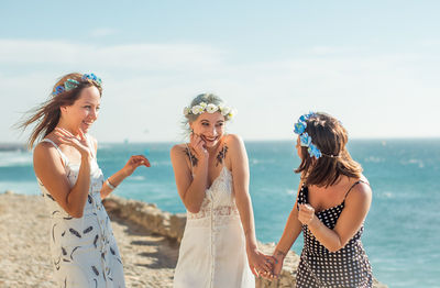 Happy friends standing by bride against sea