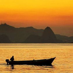 Silhouette of boat sailing in sea at sunset