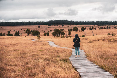 Rear view of woman walking on land against sky