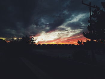 Scenic view of silhouette landscape against dramatic sky during sunset