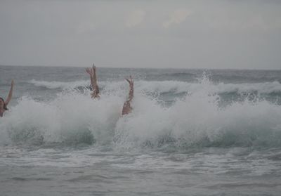 Man splashing water in sea against sky