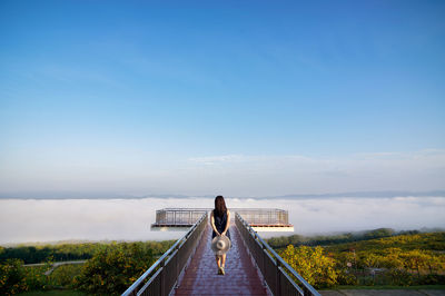 Rear view of woman standing against blue sky