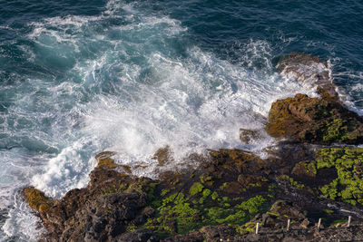 High angle view of waves splashing on rocks