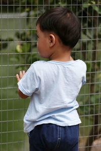 Asian boys was looking at the animals in the zoo with great interest and surprise.
