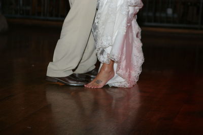 Low section of bride and groom standing on hardwood floor