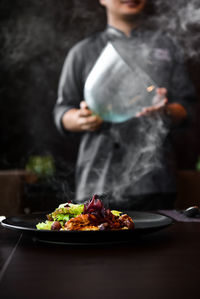 Midsection of man preparing food in plate