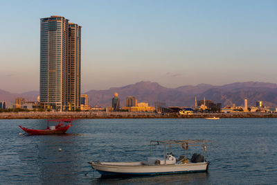 Boats in sea against buildings in city