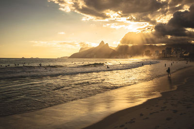 Silhouette people at beach in ipanema against sky during sunset