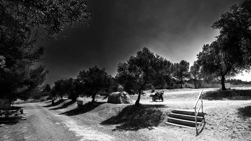 People sitting on bench in park against sky