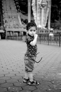 Portrait of cute boy standing on footpath