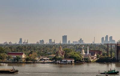 River by buildings in city against clear sky