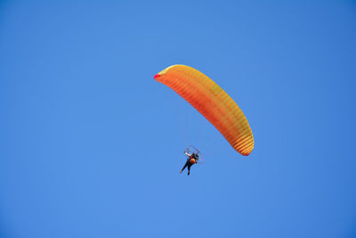 Low angle view of person paragliding against clear blue sky