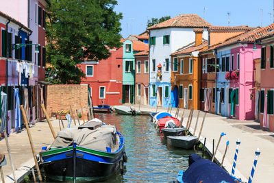 Boats moored on canal by colorful buildings at burano island