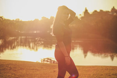 Side view of woman standing at beach during sunset