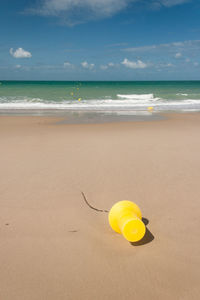 Yellow umbrella on beach against sky