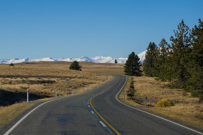 Road amidst landscape against clear blue sky