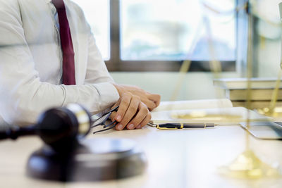 Midsection of lawyer sitting at table in courthouse