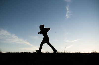 Silhouetted boy running on hill in waco texas