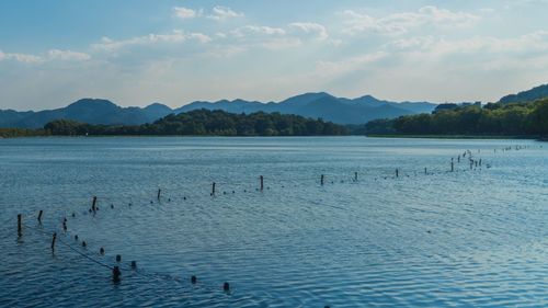 Scenic view of lake next to mountains against cloudy sky