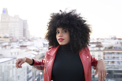 Portrait of smiling young woman standing against city in background