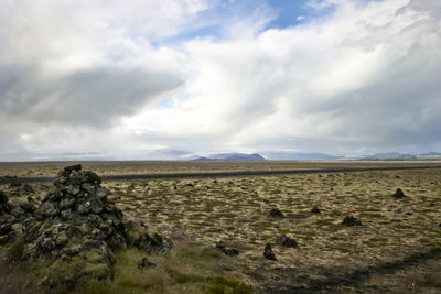 Scenic view of field against cloudy sky