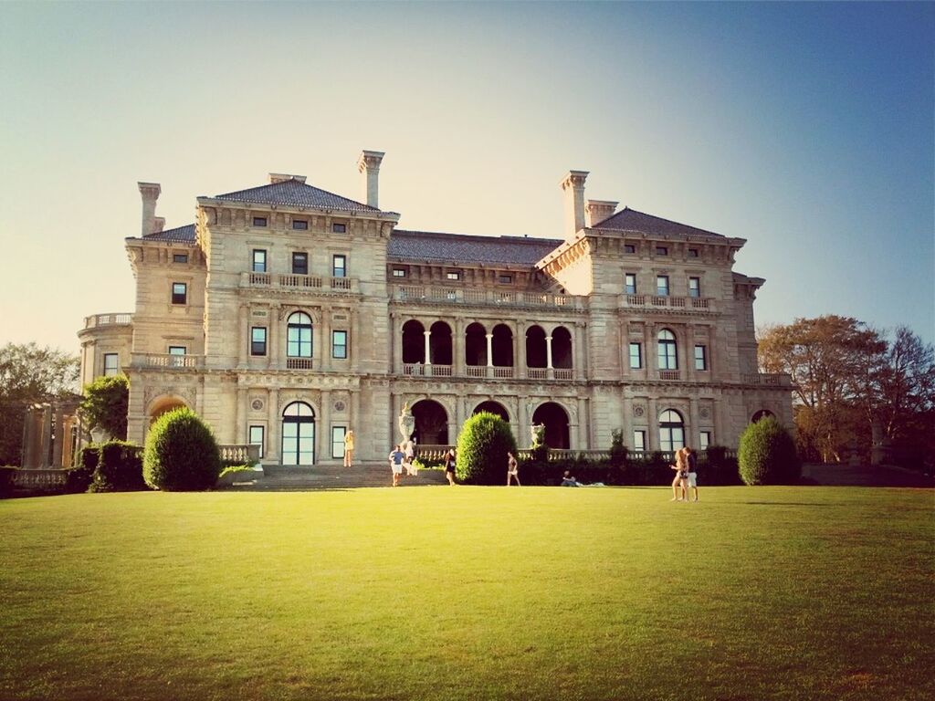 architecture, built structure, building exterior, grass, lawn, clear sky, arch, tree, facade, history, famous place, travel destinations, sky, architectural column, tourism, green color, incidental people, travel, day, outdoors