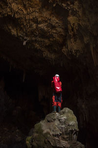 Rear view of man standing on rock in cave