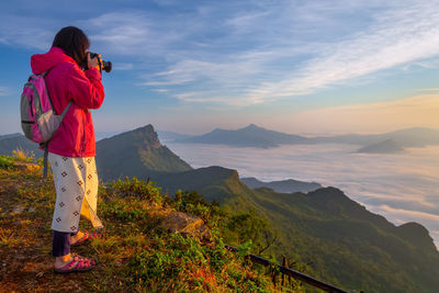 Woman photographing cloudscape during sunset