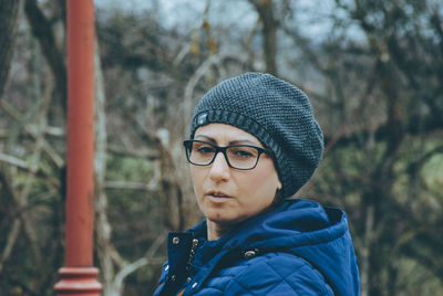 Close-up of mature woman wearing warm clothing while hiking in forest