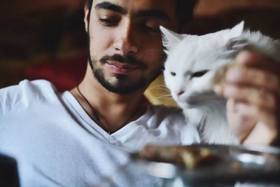 Close-up of young man with cat sitting at home