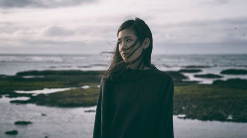 Portrait of young woman standing on beach