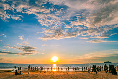 People at beach against sky during sunset