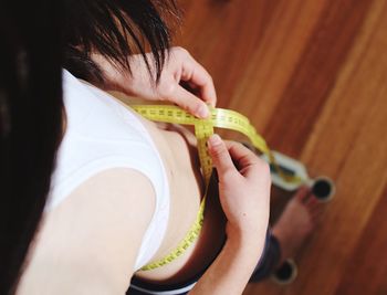 Woman measuring waist while standing on weigh scale at home