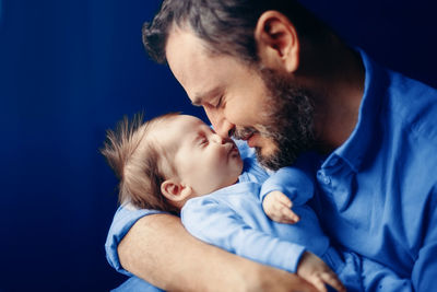 Father with baby against blue background