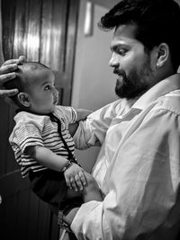 Side view of father carrying son while standing at home