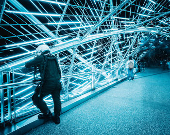 Full length of man standing on illuminated railroad station at night