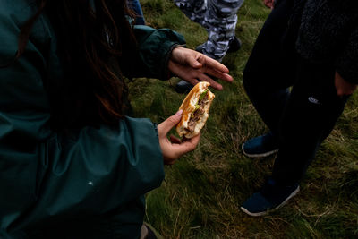 Midsection of woman holding hands on field