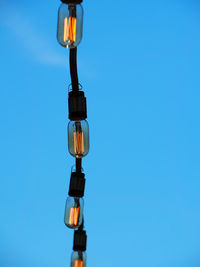 Low angle view of illuminated lamp against blue sky