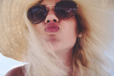 Close-up portrait of woman wearing sunglasses while puckering lips