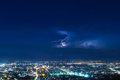 Lightning striking over illuminated cityscape at night