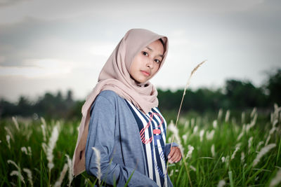 Portrait of young woman standing against sky during sunset